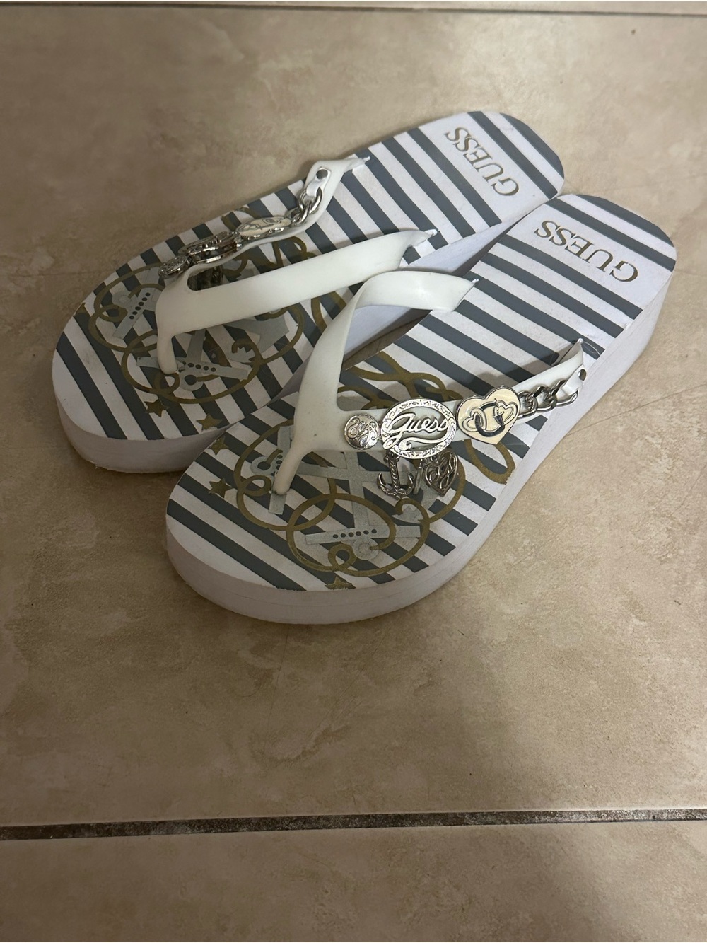 GUESS White and Gray Striped Flip Flops with Gold Accents and Logo Charms